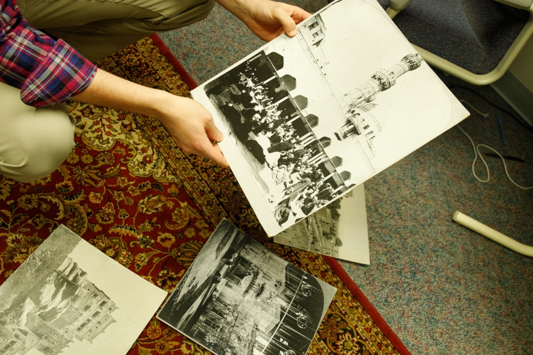 A man's hands sifting through black and white photos of ancient buildings