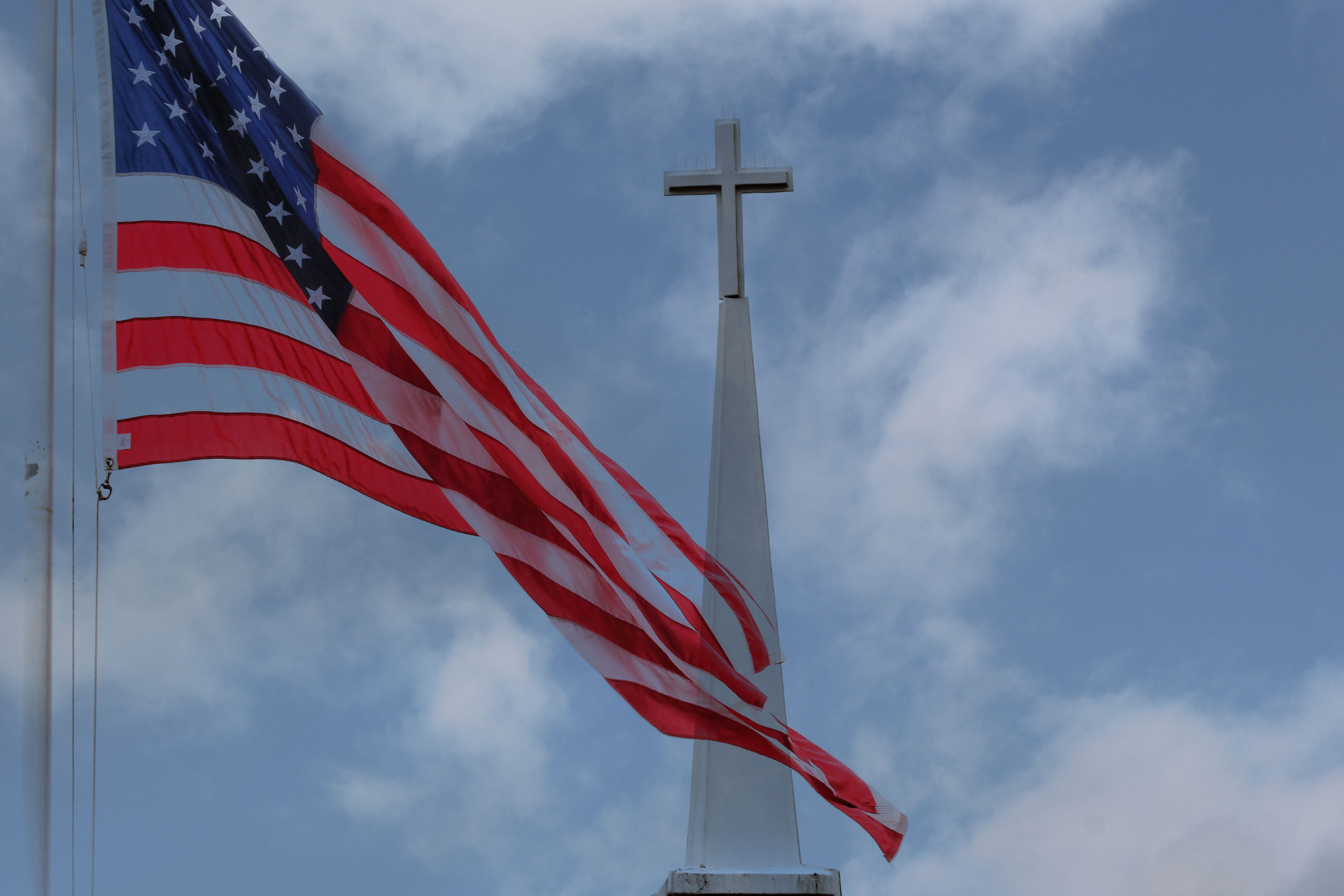 Image of an American flag flying in front of a church steeple