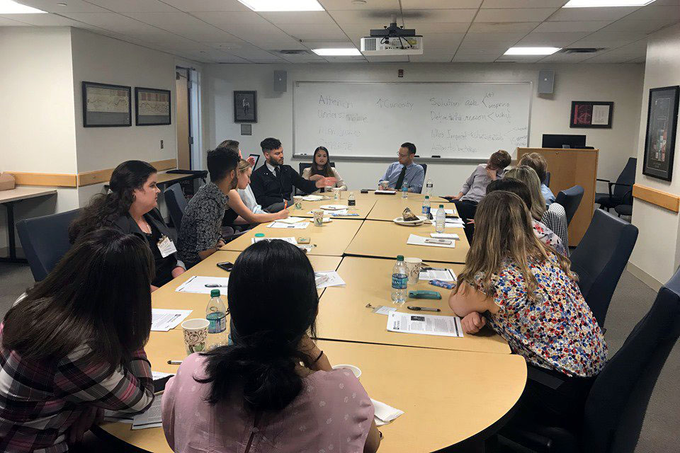 Sam Goldman and students sit around a shared table with papers 