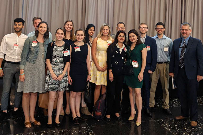 A group of students with name tags standing together in professional attire.